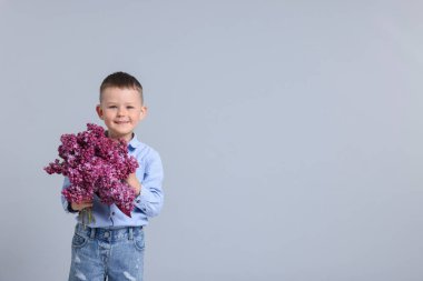 Açık gri arkaplanda leylak çiçekleri olan küçük çocuk, mesaj için yer aç.