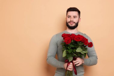 Bej arka planda kırmızı gül buketi olan mutlu adam, metin için boşluk.