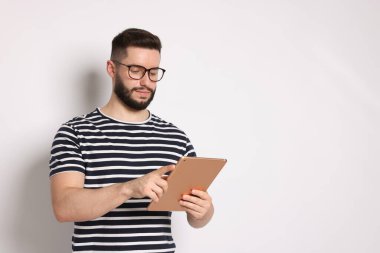 Beyaz arkaplanda tablet kullanan yakışıklı adam, metin için boşluk