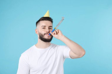 Doğum günün kutlu olsun. Açık mavi arka planda parti şapkası ve üfleyicisi olan yakışıklı adam, metin için yer