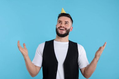 Doğum günün kutlu olsun. Açık mavi arka planda parti şapkası olan yakışıklı bir adam.