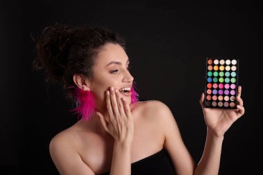 Siyah arka planda parlak göz falı olan şaşırmış bir kadın.