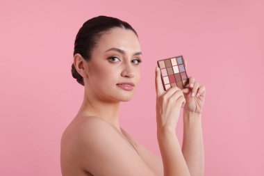Pembe arka planda göz falı paleti olan kadın.