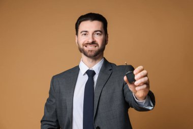 Bej arka planda araba anahtarı olan neşeli bir satıcı.