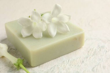 Bir kalıp sabun ve yasemin çiçekleri ışık masasında, yakın plan.