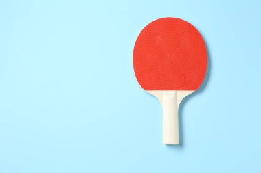 Açık mavi arka planda bir pinpon raketi, üst manzara. Metin için boşluk