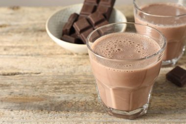 Bardakta çikolatalı süt ve ahşap masada parçalar, yakın plan. Metin için boşluk