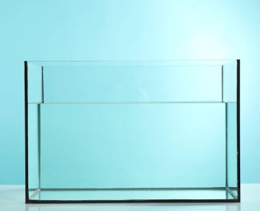 Açık mavi zemin üzerinde su bulunan cam akvaryum