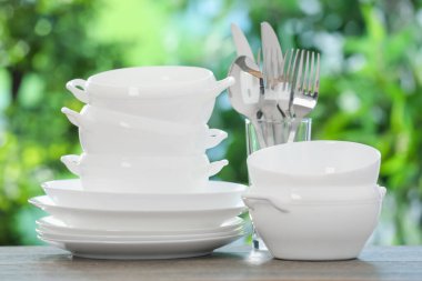 Ahşap masada, bulanık yeşil arka planda farklı temiz tabaklar.