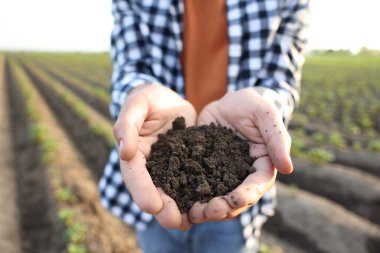 Tarlada toprak yığını tutan adam, yakın plan.