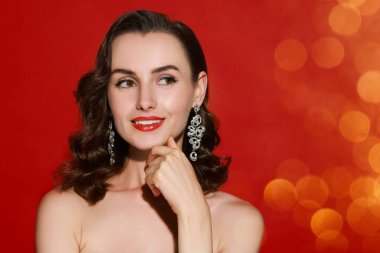 Kırmızı arka planda mükemmel makyajlı gülümseyen kadın, bokeh etkisi