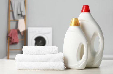 Kumaş yumuşatıcı, deterjan ve havlular çamaşır odasındaki masada.