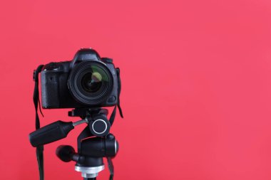 Kırmızı arka planda modern profesyonel kamera, yakın plan. Metin için boşluk