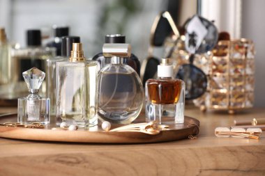 Farklı parfüm şişeleri ve aksesuarlar ahşap masada, yakın plan.