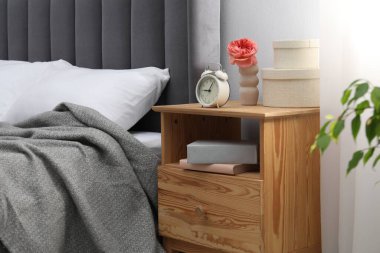 Alarm saati, kitaplar ve evin içinde yatağın yanındaki dekorun olduğu komodinin yanında. İç tasarım