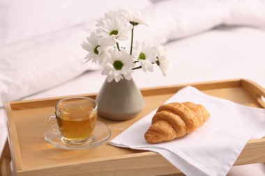 Nefis bir kahvaltı tepsisi ve çiçeklerle kapalı bir yerde, yakın plan.