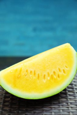 Açık havuz kenarında hasır masada lezzetli bir karpuz dilimi, yakın plan.