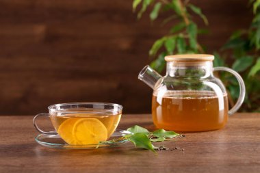 Lezzetli yeşil çay, limon ve çaydanlık ahşap masada.