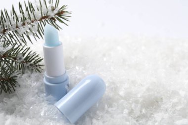 Nemlendirici dudak kremi ve suni kar üzerinde köknar ağacı dalları, yakın plan. Metin için boşluk