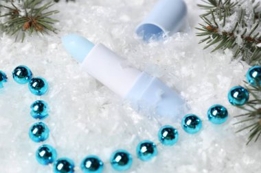 Nemlendirici dudak kremi, Noel dekorasyonu ve yapay kar üzerindeki köknar ağacı dalları, yakın plan. Kış bakımı