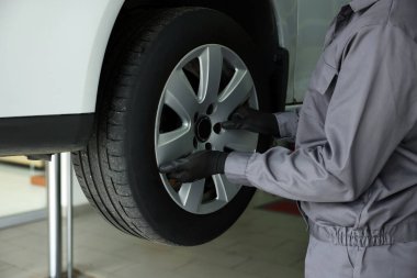 Tamirci araba servisinde lastik değiştiriyor, yakın plan.