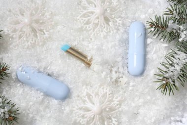 Nemlendirici dudak kremleri, Noel dekorasyonu ve yapay kar üzerindeki köknar ağacı dalları. Kış bakımı