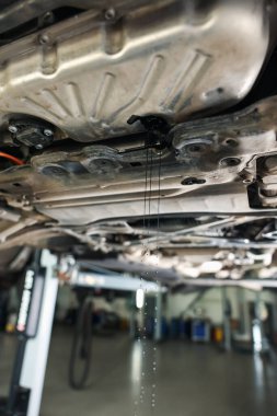 Araba motorundan damlayan eski kirli motor yağı atölyede, yakın plan.