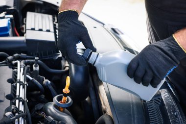 İşçi arabada motor yağı seviyesini dipstick ile kontrol ediyor.