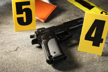 Adli tıp uzmanı. Sarı olay yeri bandı, silah ve pasaport gri masada, yakın plan.