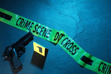 Adli tıp uzmanlığı. Suç mahalli bandı ve silah. Renkli arka plan, düz. Metin için boşluk