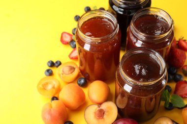 Sarı arka planda farklı kavanozlar ve malzemeler, yakın plan.