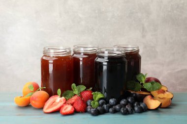 Kavanozlardaki farklı reçeller ve mavi ahşap masadaki malzemeler. Metin için boşluk