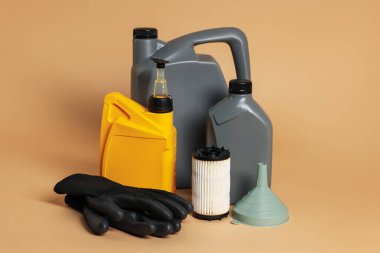 Plastik kaplarda motor yağı, filtre, eldiven ve bej arka planda huni