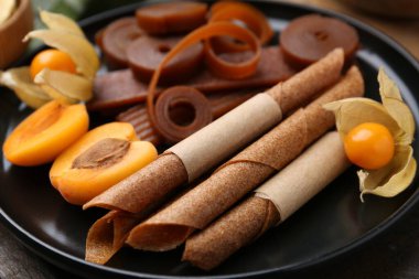 Lezzetli meyve derisi, bitki kökü ve kayısılar ahşap masada, yakın plan.