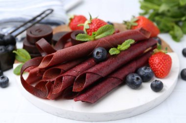 Lezzetli meyve dürümleri, çilekler, yaban mersini ve nane şekeri beyaz masada, yakın plan.