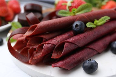 Lezzetli meyve dürümleri, çilekler, yaban mersini ve nane şekeri beyaz masada, yakın plan.