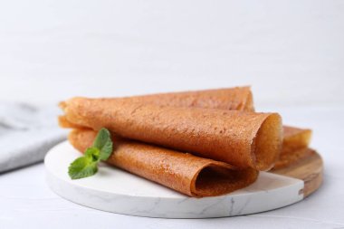 Lezzetli meyve dürümleri ve nane şekeri beyaz masada, yakın plan.