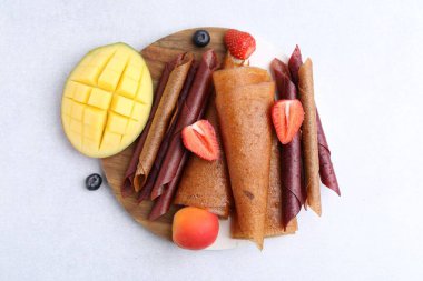 Lezzetli meyve dürümleri, mango, kayısı ve böğürtlen ışık masasında, düz uzanmış