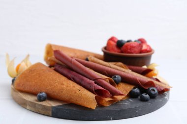 Lezzetli meyve dürümleri ve beyaz masada meyveler, yakın plan.