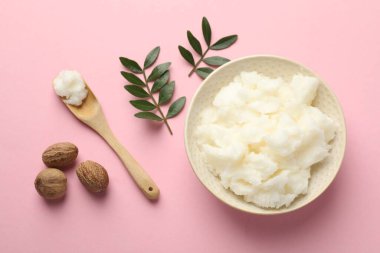 Doğal Shea yağı, fındık ve yapraklar pembe arka planda, düz yatıyordu.