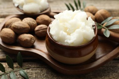 Doğal Shea yağı, fındık ve yapraklar ahşap masada, yakın plan.