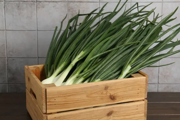 Tahta masadaki sandıkta taze taze taze soğanlar.