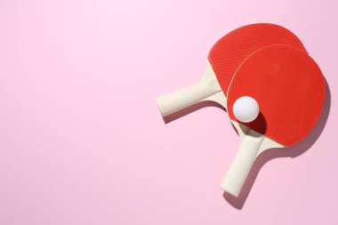 Ping pong rackets and ball on pink background, flat lay. Space for text