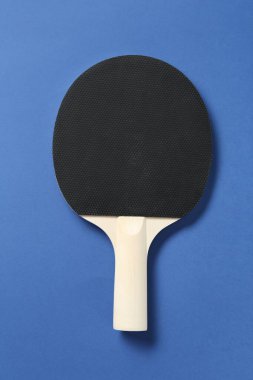 Mavi arka planda bir ping pong raketi, üst görünümde.