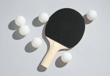 Masa tenisi raketi ve toplar arka planda, düz yatıyordu.