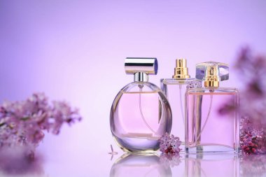 Ayna yüzeyindeki parfüm şişeleri ve leylak çiçekleri menekşe eğimli arka plan, seçici odak
