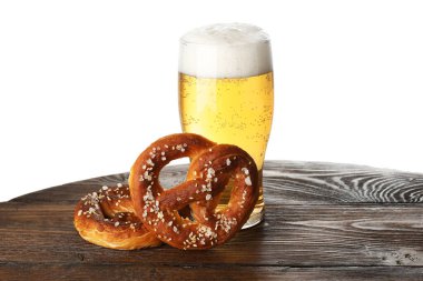 Lezzetli krakerler ve beyaz arka plana karşı ahşap masada bir bardak bira.