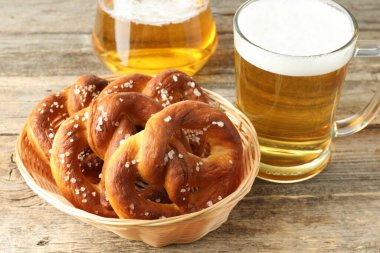 Sepette lezzetli krakerler ve ahşap masada bir bardak bira, yakın plan.