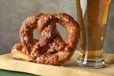 Lezzetli krakerler ve yeşil ahşap masada bir bardak bira. Gri arka plan, yakın plan.