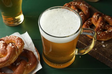 Lezzetli krakerler ve biralar yeşil ahşap masada, yakın plan.